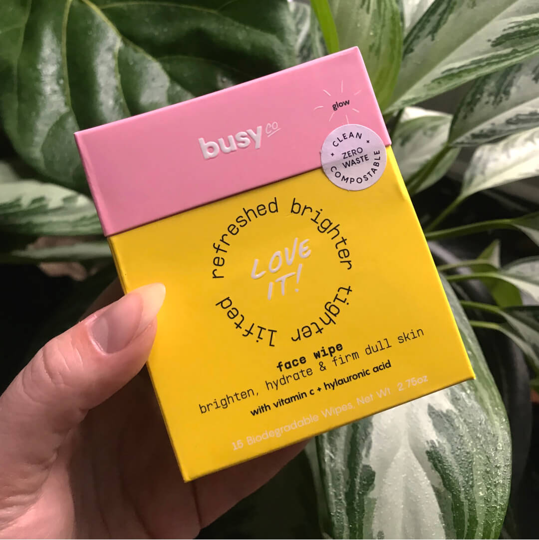 Busy Beauty packaging against a background with green plants